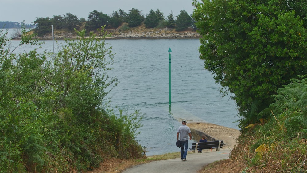 a man and a woman walking along a path by a lake
