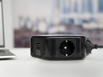 Close-up of a conference table’s sleek power module with USB and power outlets, set against a grey and white minimalist background.