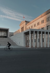 a person riding a bicycle on a street next to a building