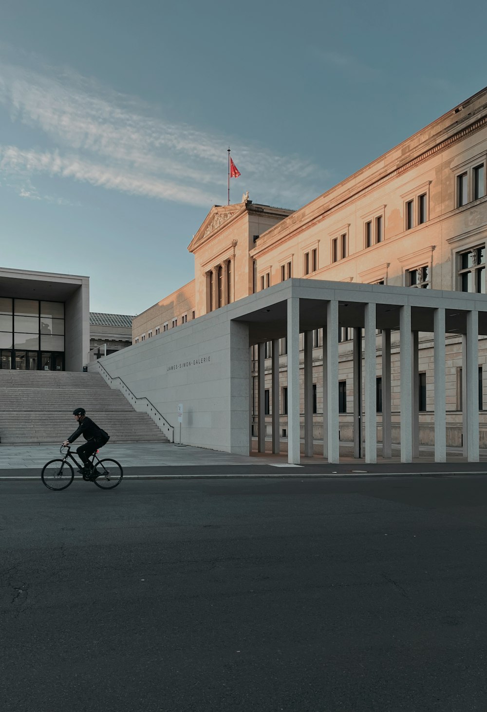 a person riding a bicycle on a street next to a building