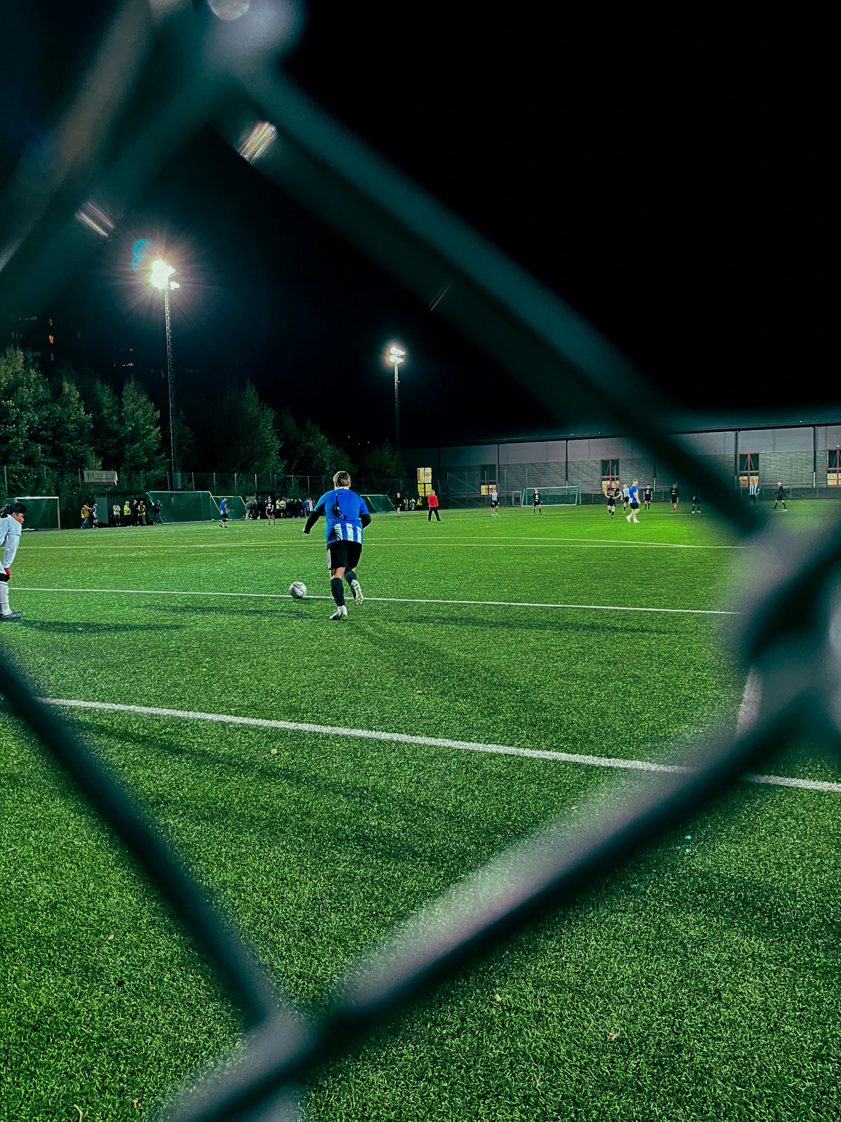 A floodlit pitch seen through the perimeter fence
