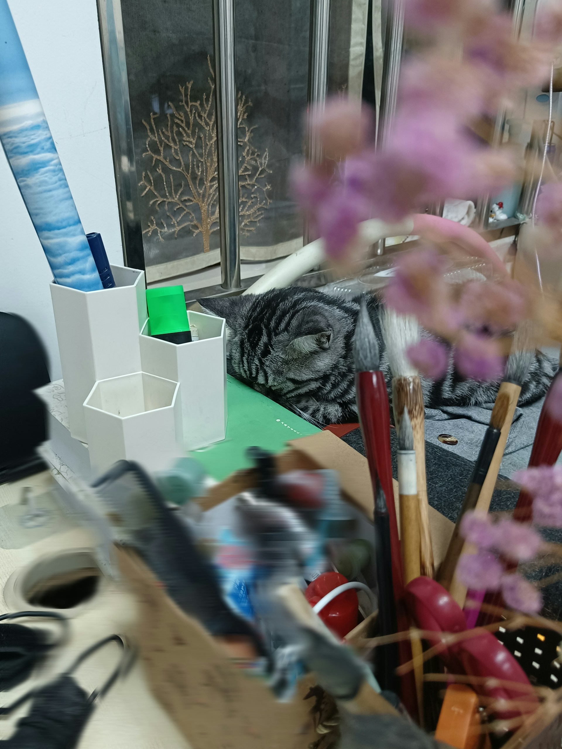 A cozy scene of two cats nestled among art supplies and sketches, bathed in warm afternoon light.