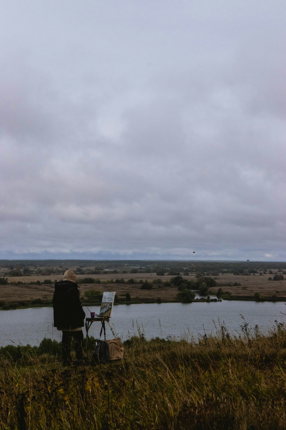 a person standing next to a body of water with a person sitting in a chair