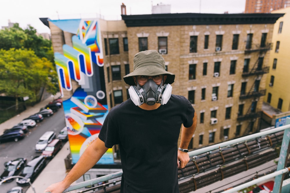 a man wearing a mask and standing on a balcony above a street