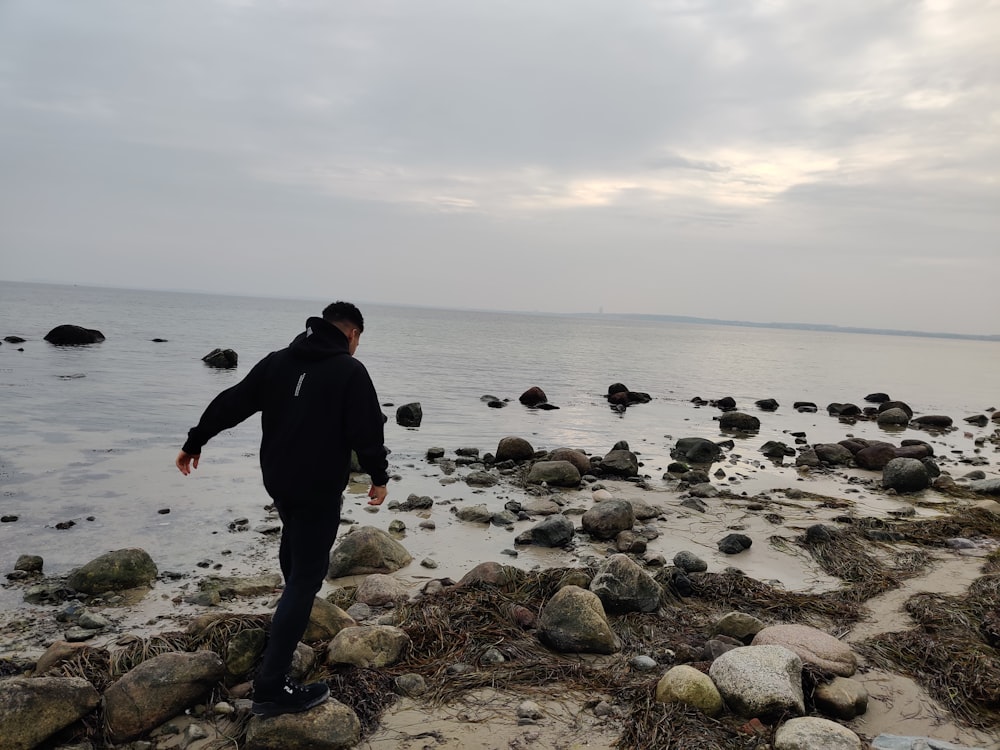 a man walking on a rocky beach