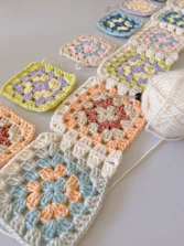 Close-up of hands crocheting a colorful granny square blanket.