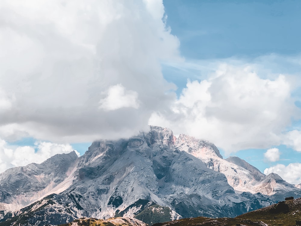 a group of clouds in the sky over a snow covered mountain