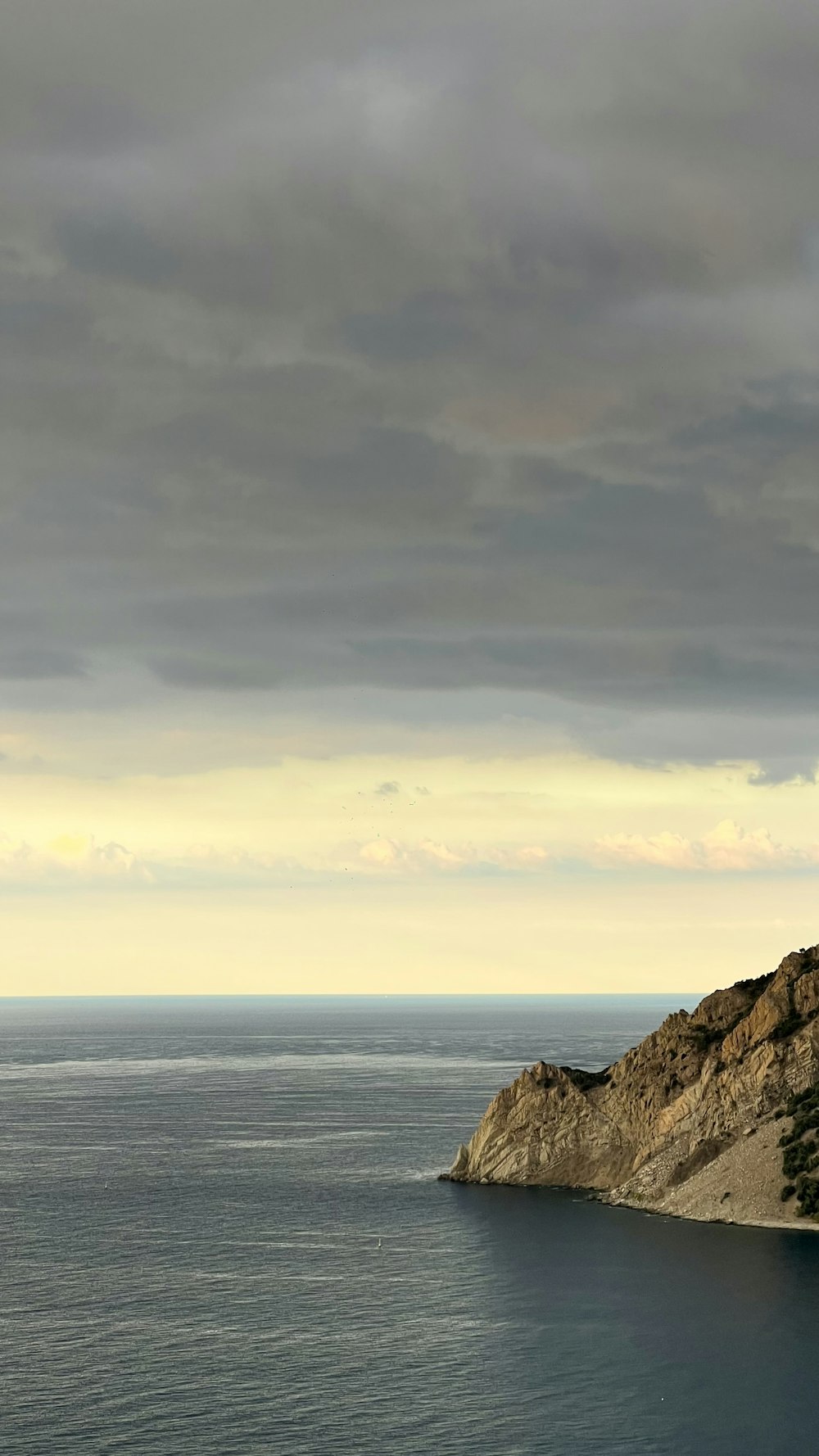 a body of water with a rocky shoreline and a cloudy sky