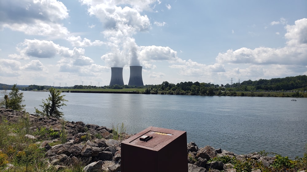 a body of water with a group of smokestacks in the distance