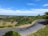 A winding road through a lush green landscape under a clear blue sky.