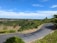 A winding road through a lush green landscape under a clear blue sky.