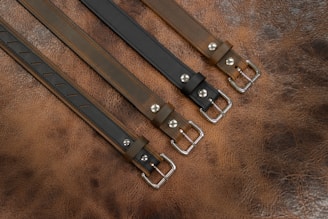 A selection of leather belts laid out on a wooden table.