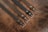 Four leather belts are laid out parallel to each other on a textured brown leather surface. Each belt features a metallic buckle and a different shade of brown or black, with a smooth, polished finish.