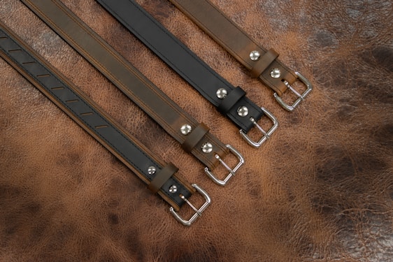 Close-up of various stylish belts arranged neatly on a wooden table.