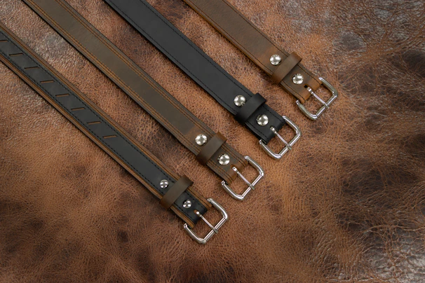 A sleek leather belt laid out on a rustic wooden surface.