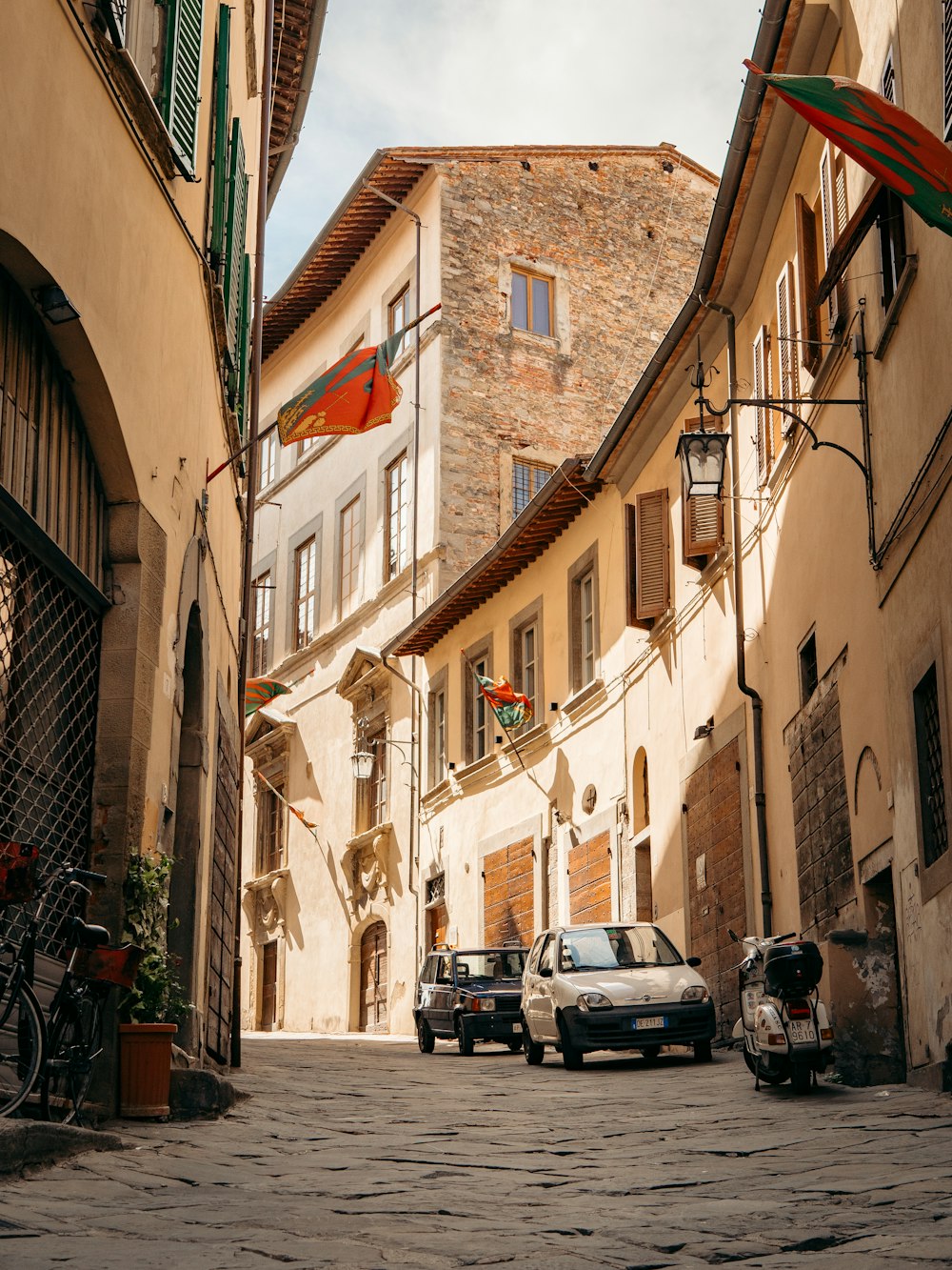 a cobblestone street with cars and buildings on either side of it