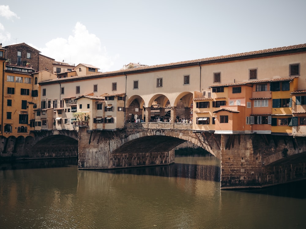 a body of water with buildings along it with Ponte Vecchio in the background