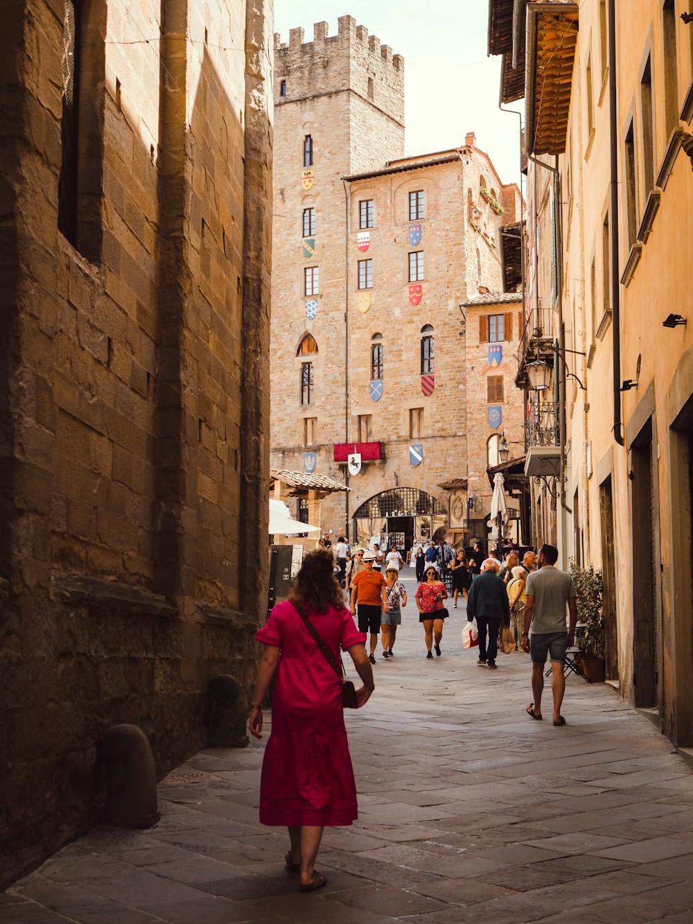 a person in a red dress walking down a street between buildings