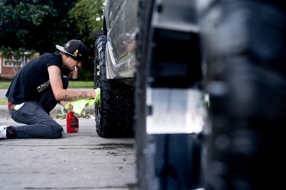 um homem com uma mangueira ao lado de um carro