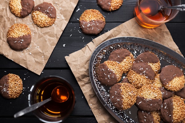 A platter of chocolate dipped cookies. There are two glasses of tea on either side of the platter.