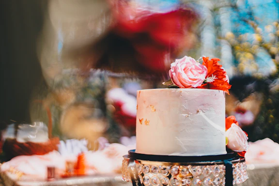 Close-up of a beautifully decorated personalized cake with pastel pink and white details on a rustic wooden table.