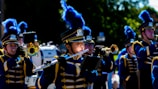 Marching band members in colorful uniforms performing in a school event