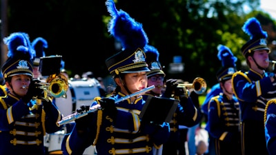Marching band members in colorful uniforms performing in a school event