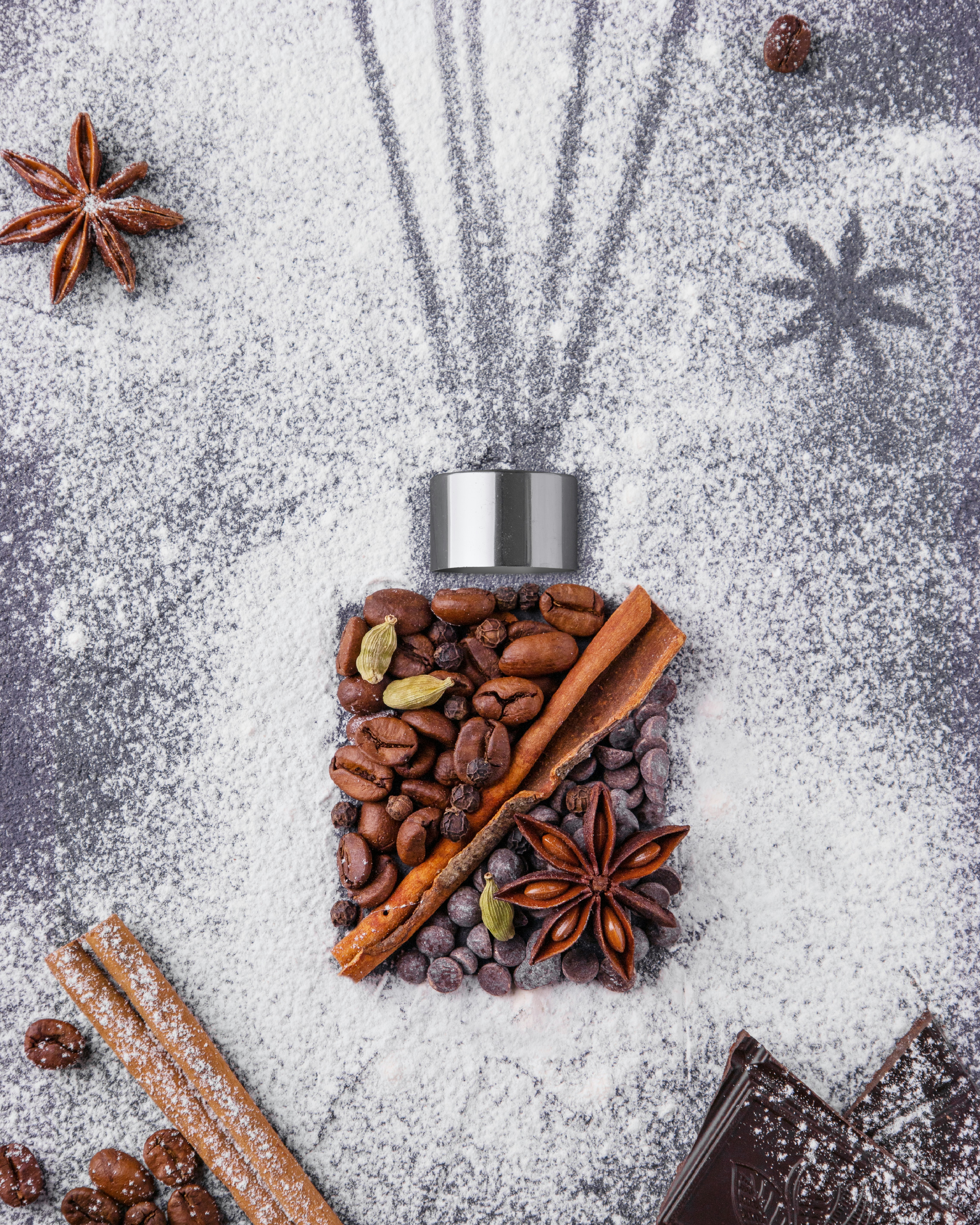 A pile of nuts and a pine cone on a white surface, evoking cedarwood and warm forest notes