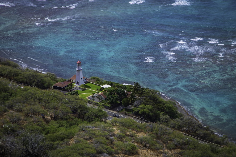 a lighthouse on a hill by the ocean with Diamond Head Lighthouse in the background