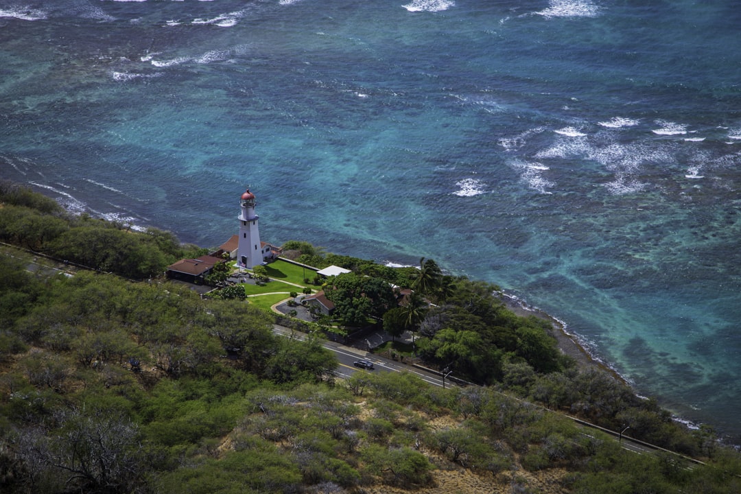 a lighthouse on a hill by the ocean with Diamond Head Lighthouse in the background,