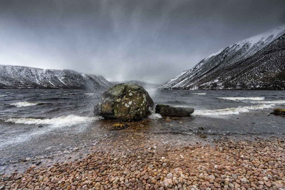 a rocky beach with a large rock in the middle