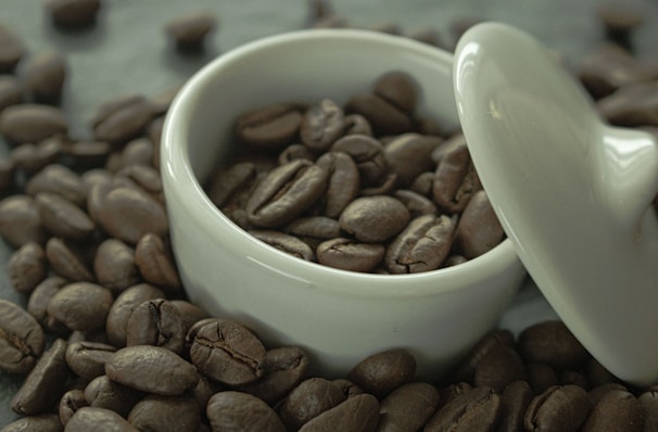 A stylish coffee storage container with coffee beans beside it.