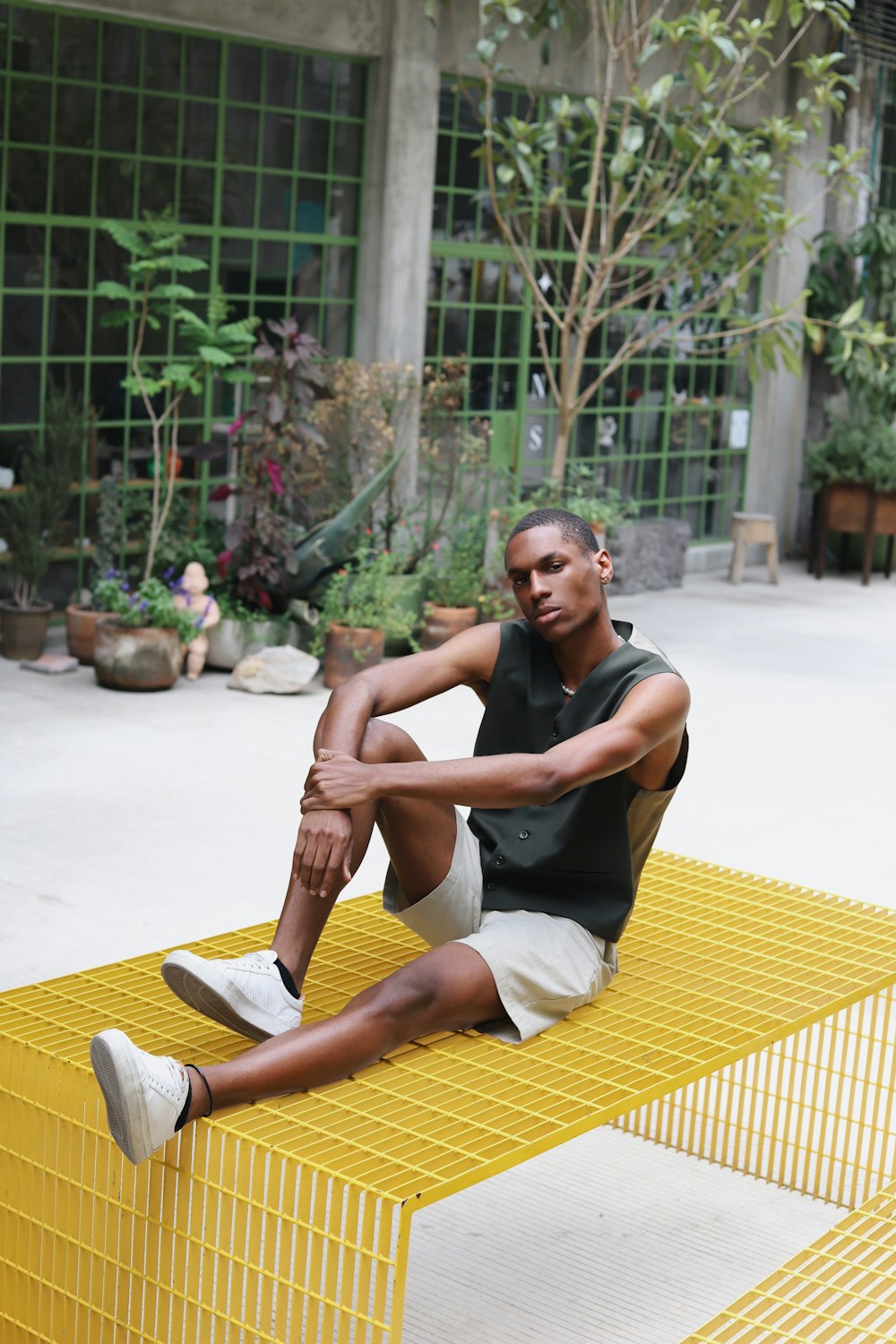 a person sitting on a yellow and white mat in front of a building