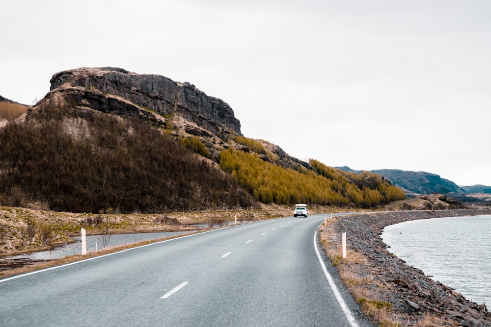 a car driving on a road next to a body of water