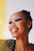 A joyful person smiling with bold eye makeup that reflects their unique style.