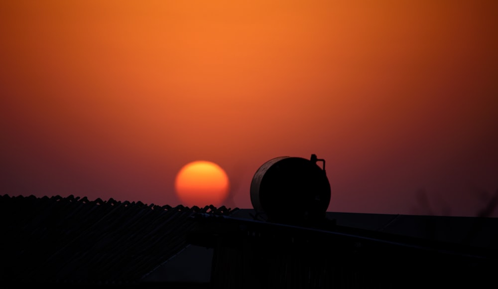 a silhouette of a fruit on a roof with the sun in the background