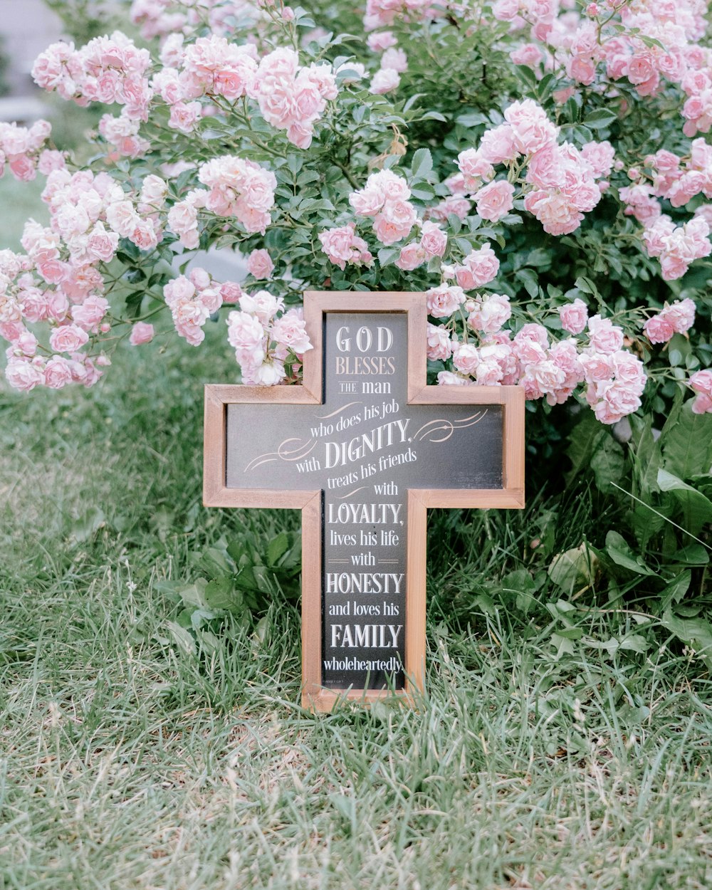 a sign in front of a bush of flowers