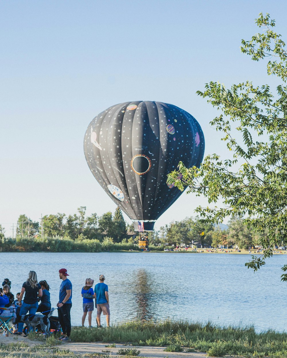 a group of people standing next to a large balloon in the air