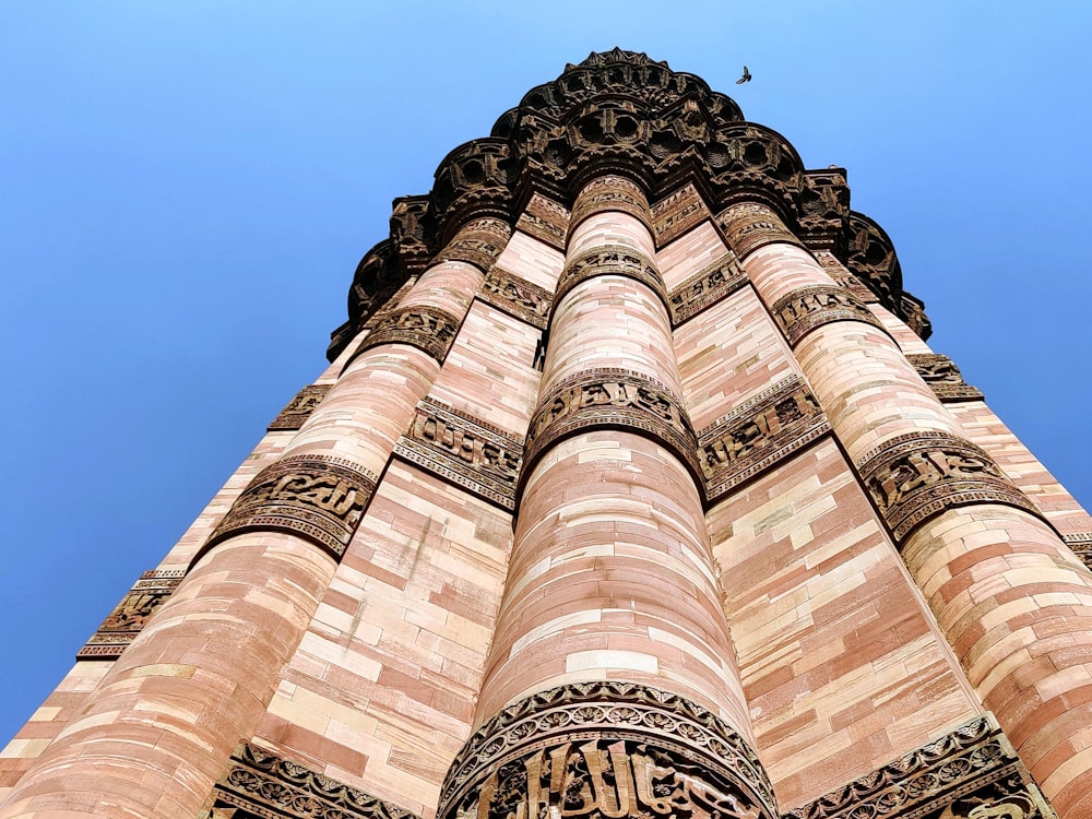 a tall tower with a blue sky with Qutub Minar in the background