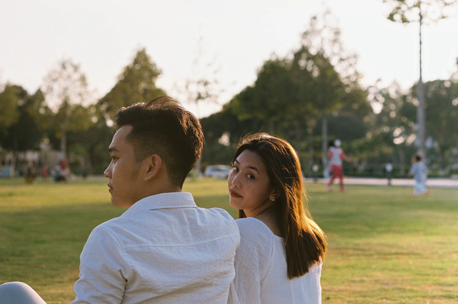 A man and a woman looking at each other in a sunlit field