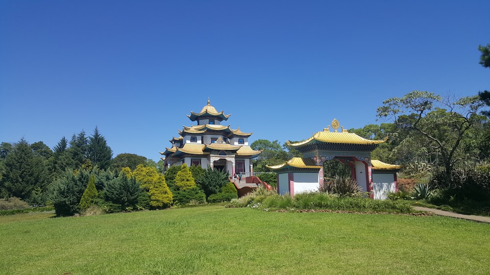 a building with a grass field and trees in the front