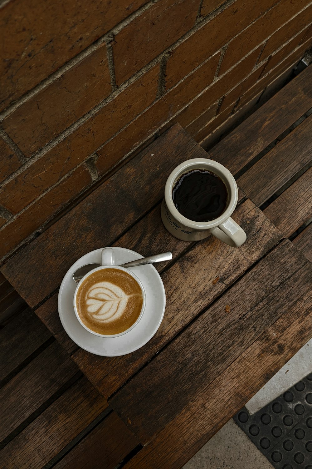 a cup of coffee and a spoon on a wood table