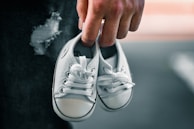A close-up of a child’s hands holding a pair of bright new shoes with excitement.