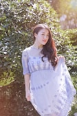 A model wearing a flowing dress in a sunlit park.