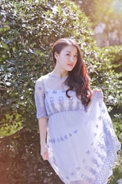 Model in a flowing pastel dress standing in a sunlit garden.