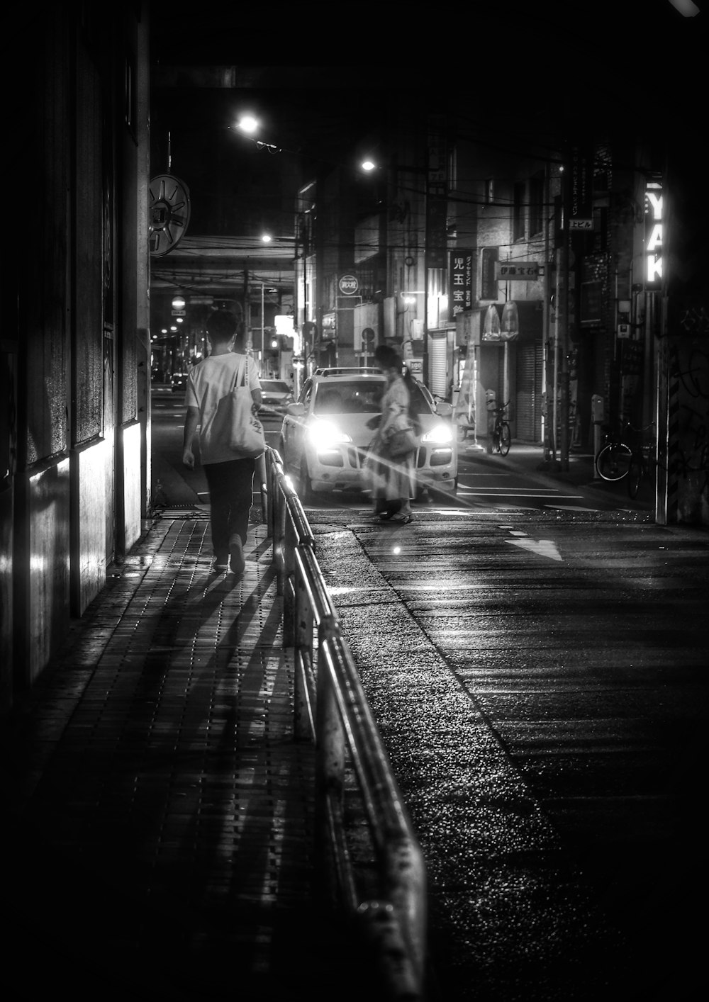 a man and a woman walking down a sidewalk at night