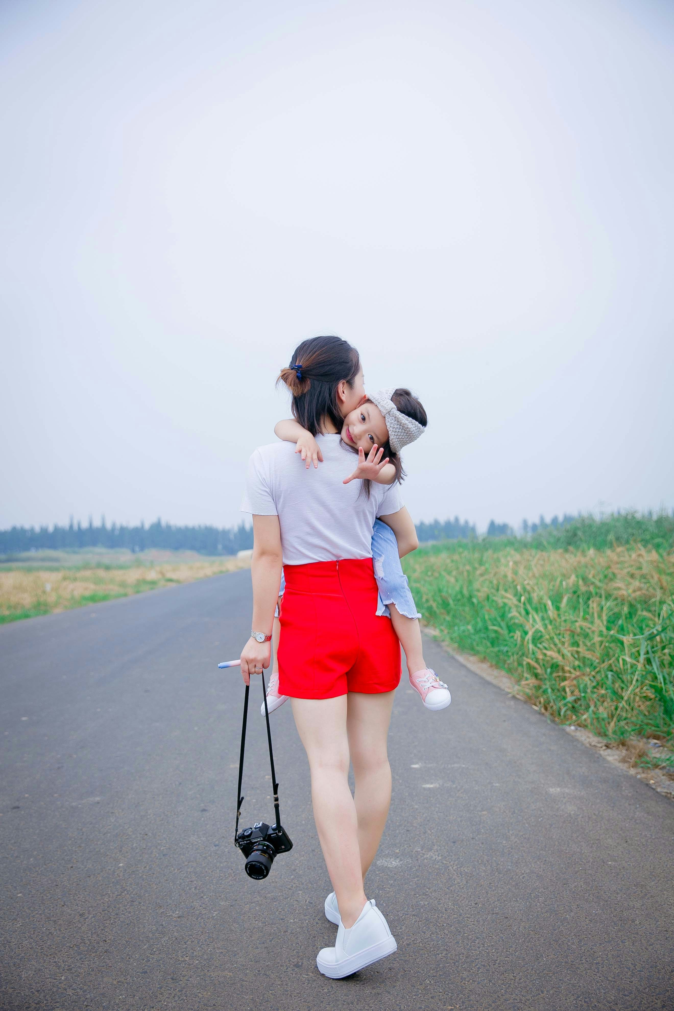 a woman holding a child on her back on a road