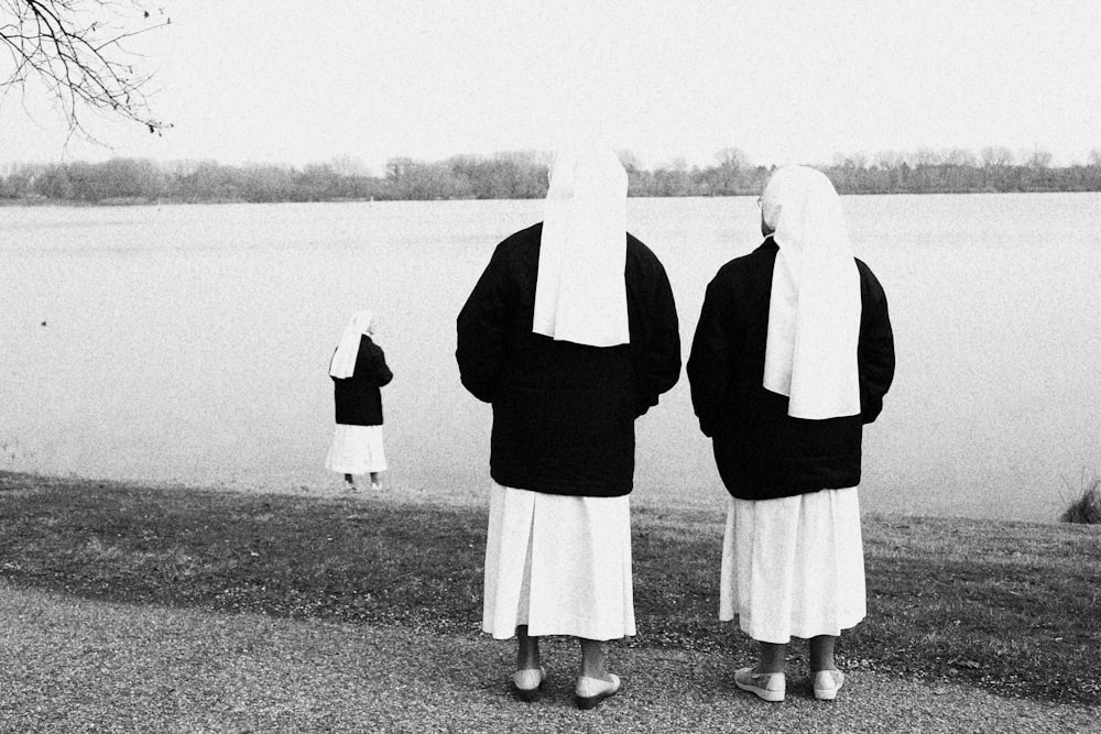 a couple of women wearing black and white standing in front of a lake