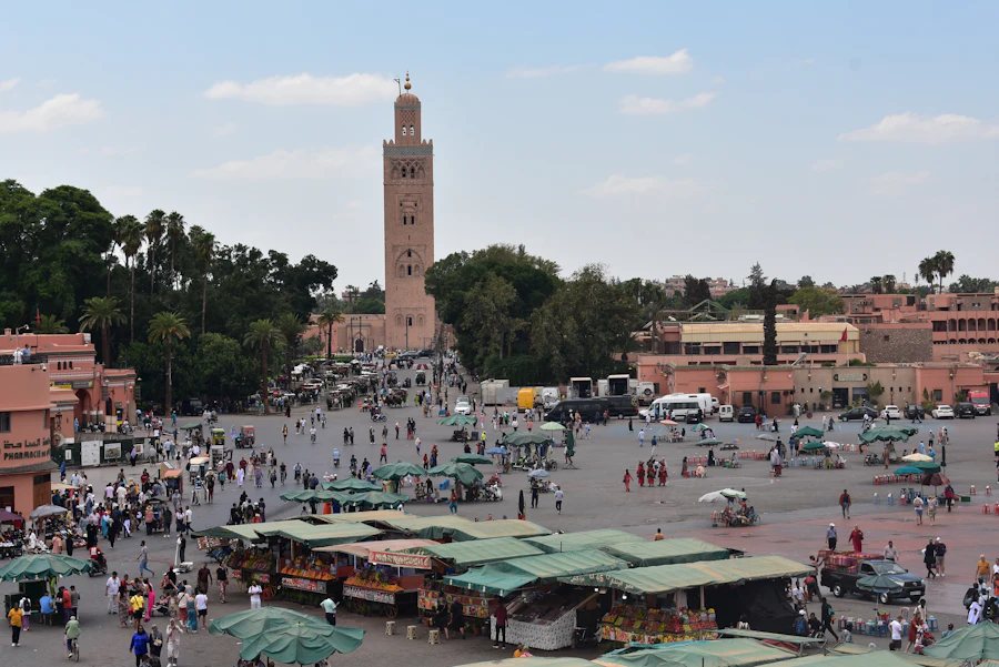 Crowds and market stalls in Jemaa el-Fna with Koutoubia Mosque minaret behind