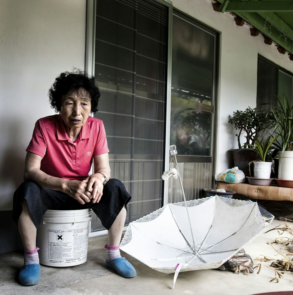 a person sitting on a stool with an umbrella